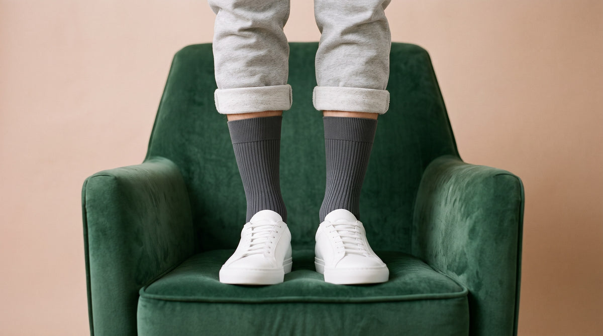 Charcoal ribbed crew socks with white trainers, standing on a green velvet armchair