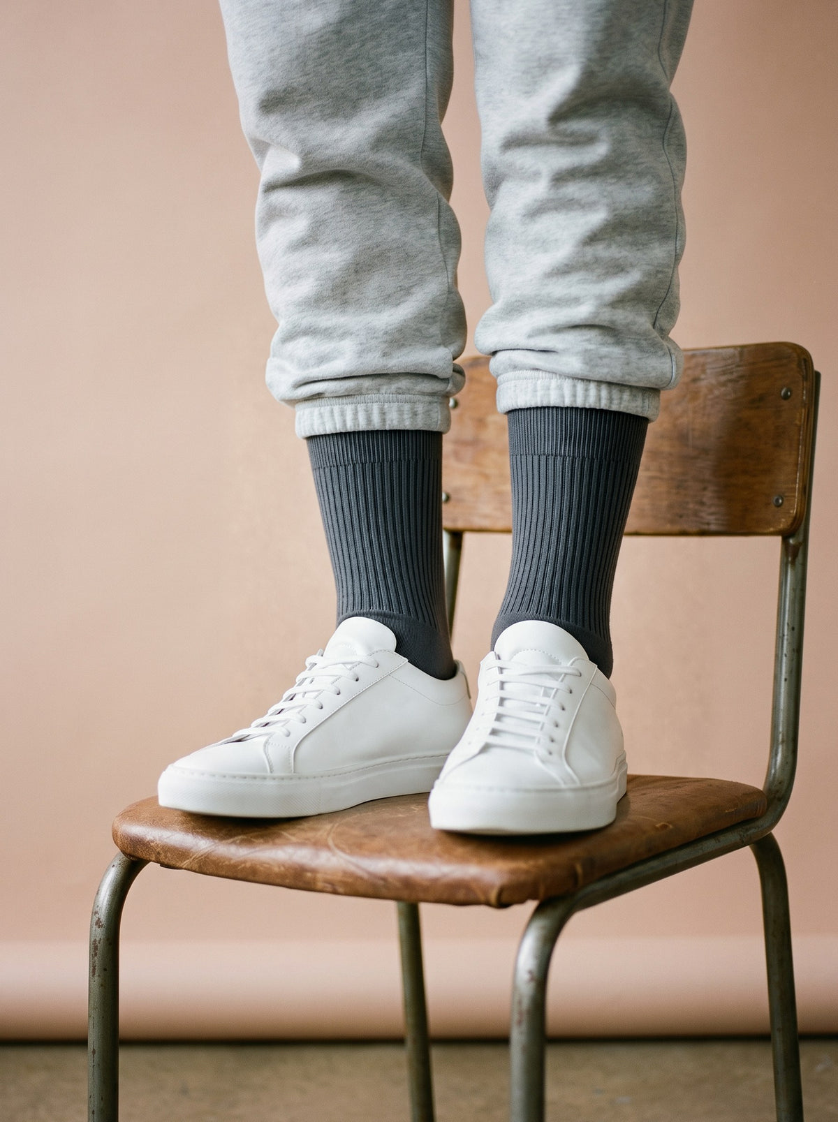 Charcoal ribbed crew socks with white trainers and grey joggers, standing on a wooden chair