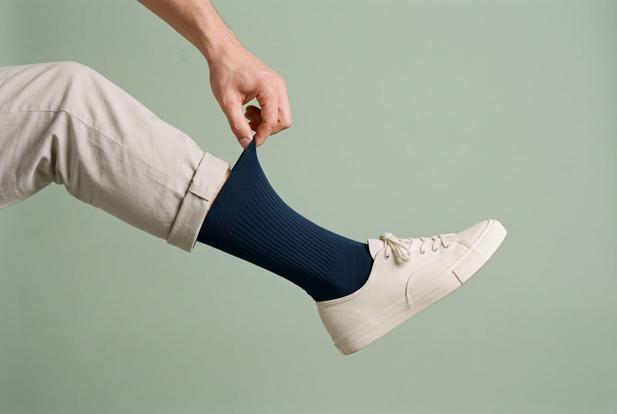 Navy ribbed crew socks being pulled up, with a white trainer