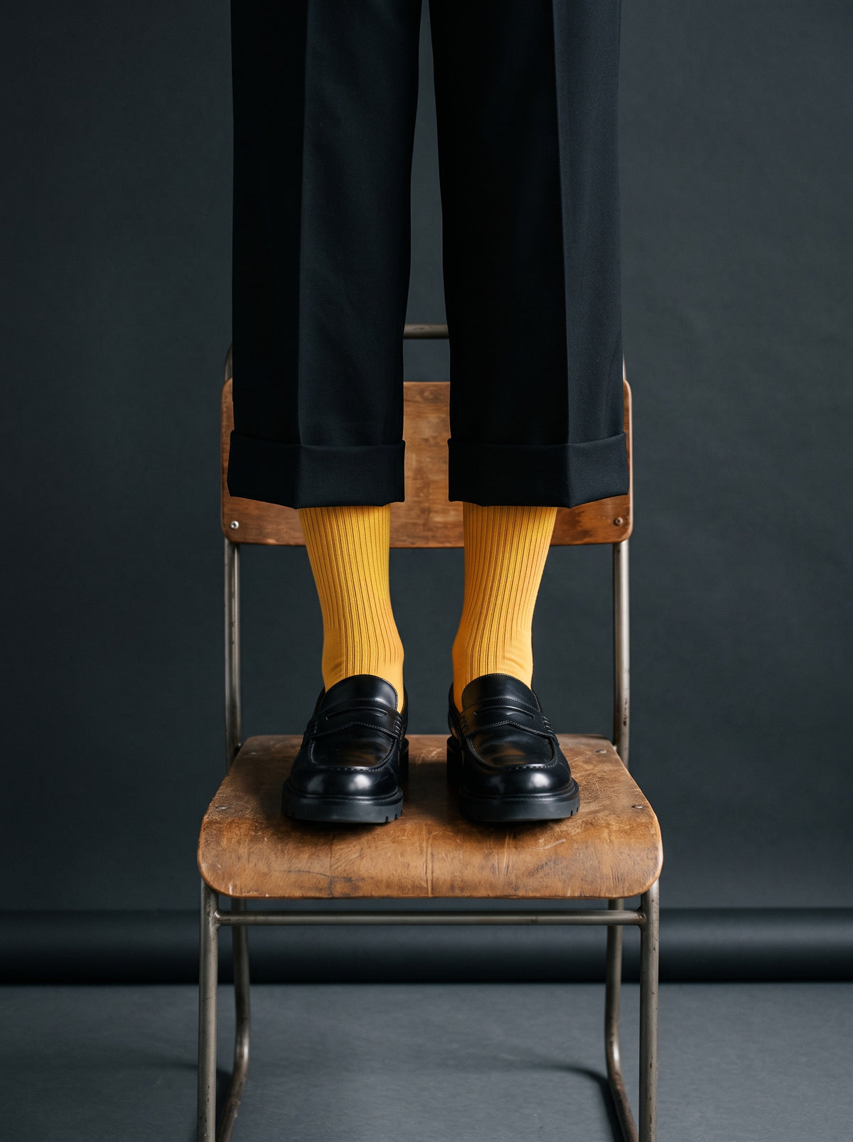 Ochre ribbed crew socks with black loafers, standing on a wooden chair